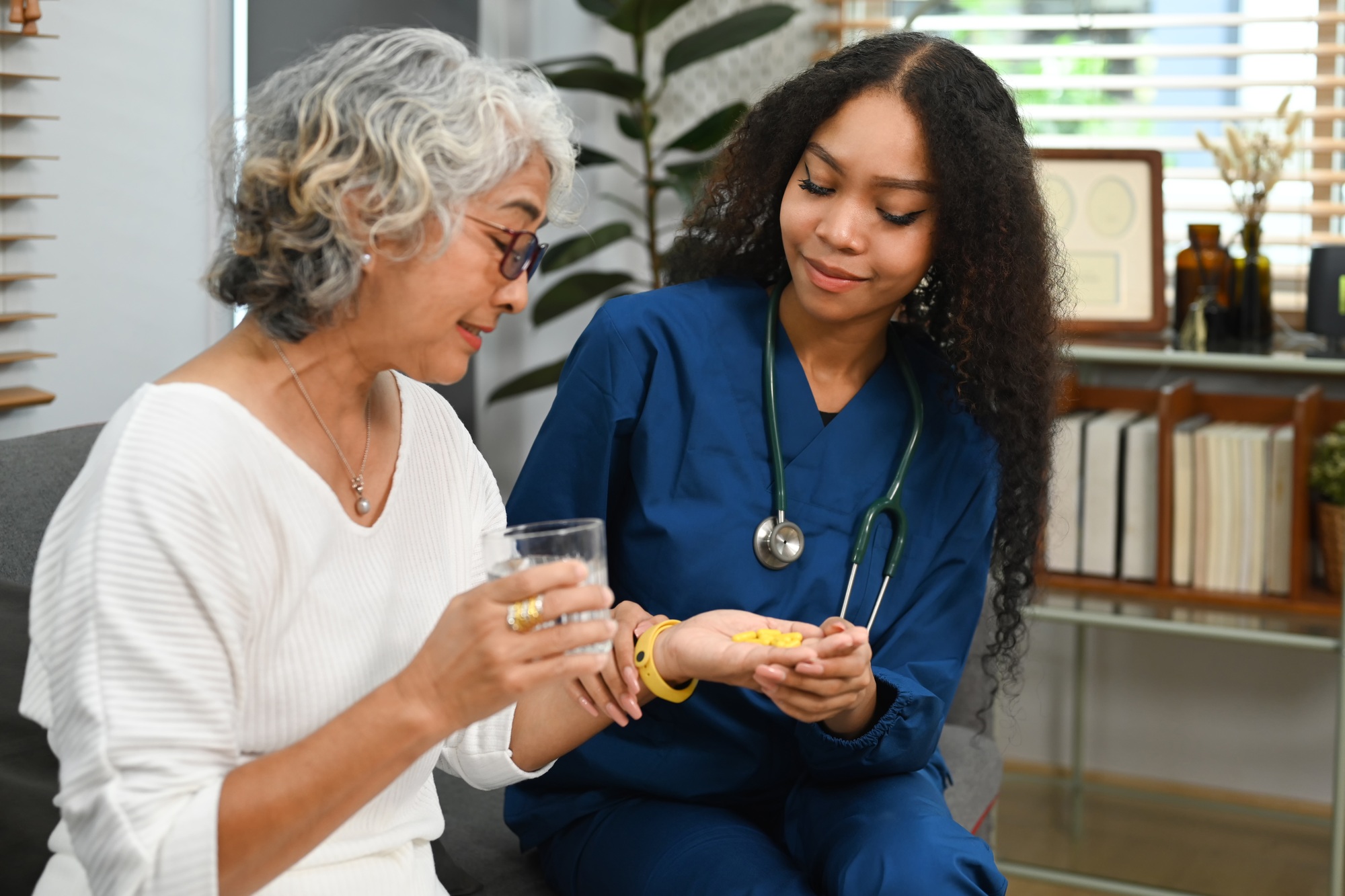 Healthcare worker or caregiver explaining medicine dosage to senior woman.